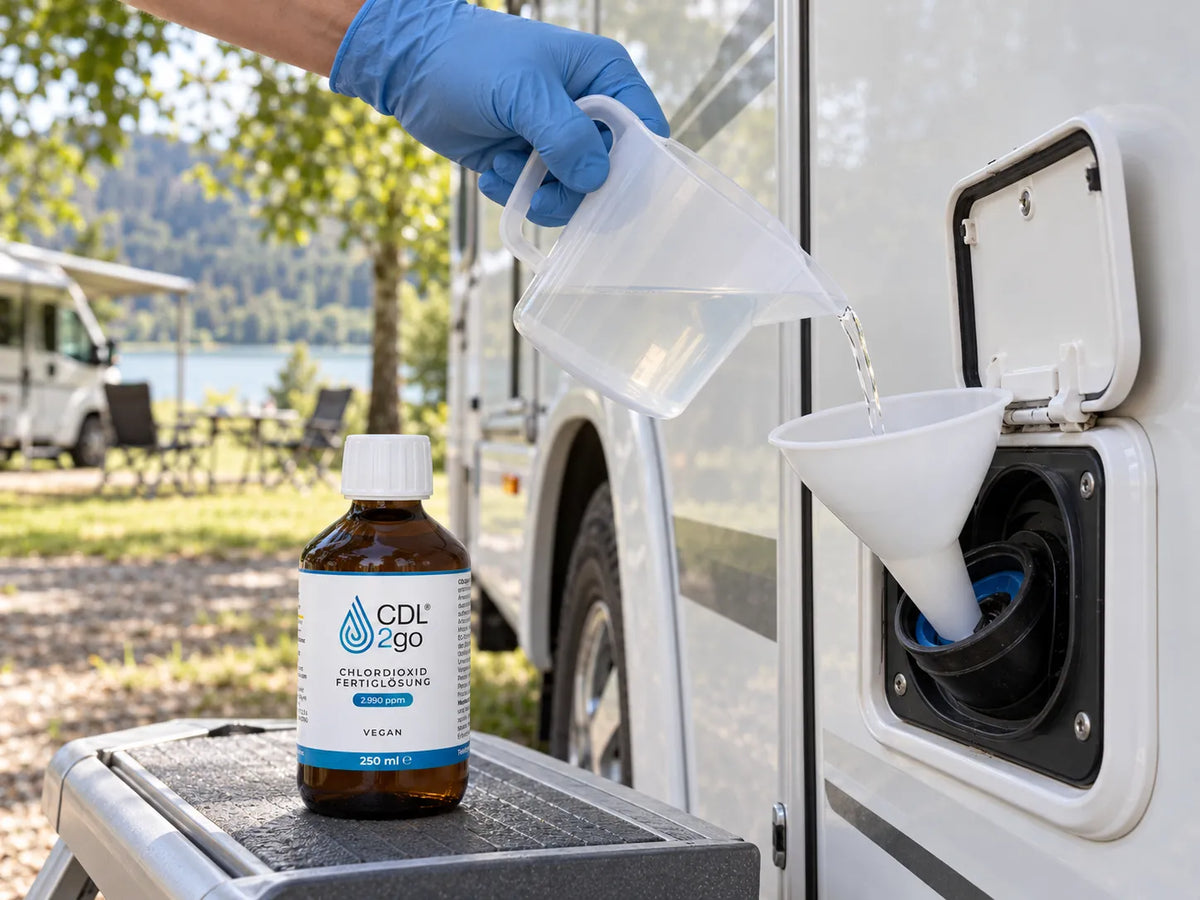 CDL2go 250 ml op de opstap, een hand met handschoen giet uit een maatbeker in de drinkwatertank van een camper