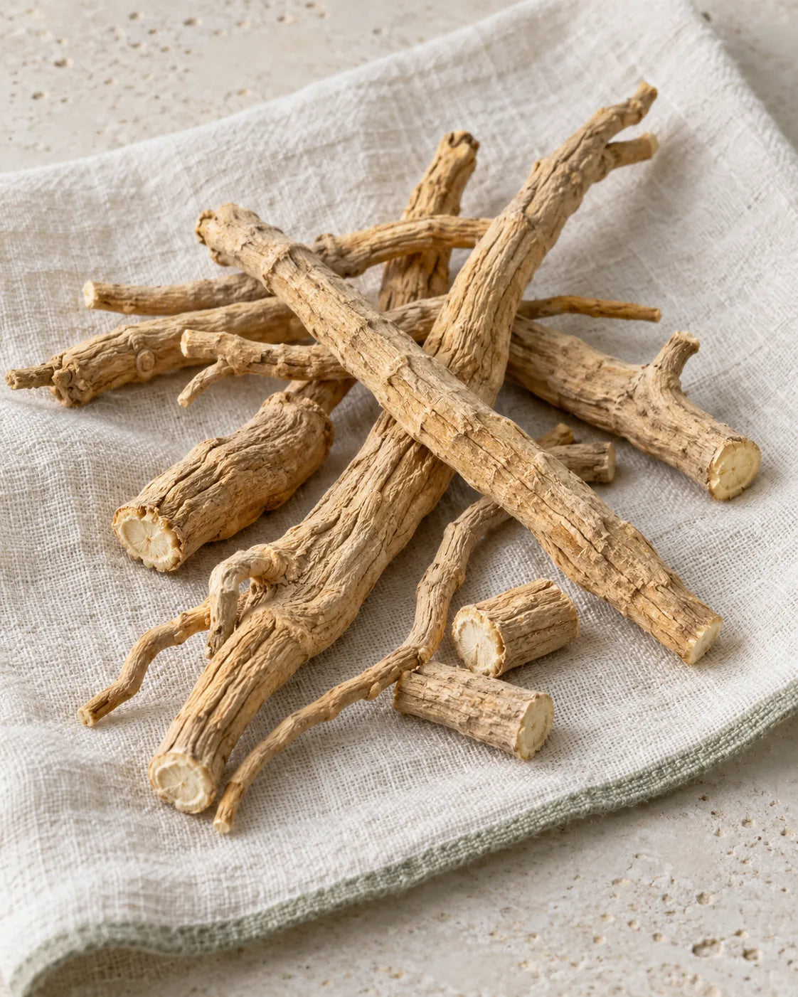 Getrocknete Ashwagandha-Wurzeln, ganz und in Stücken, auf hellem Leinen