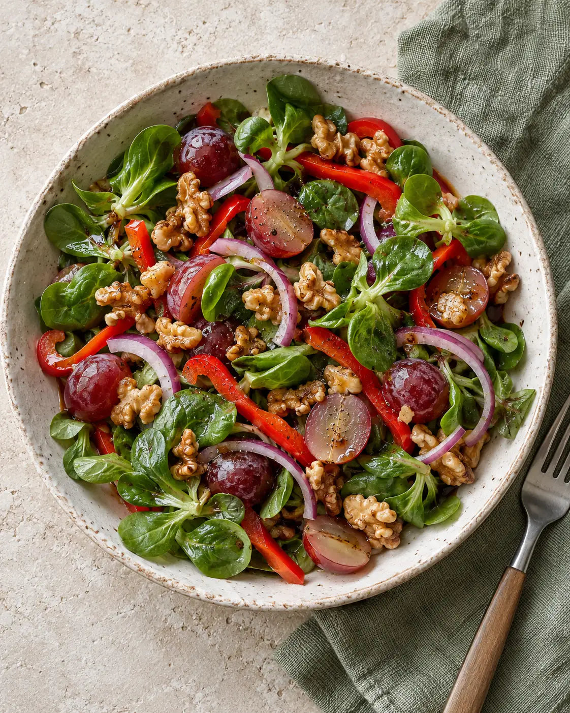 Herbstsalat mit halbierten roten Trauben, Feldsalat, roter Paprika, Zwiebeln und Walnüssen