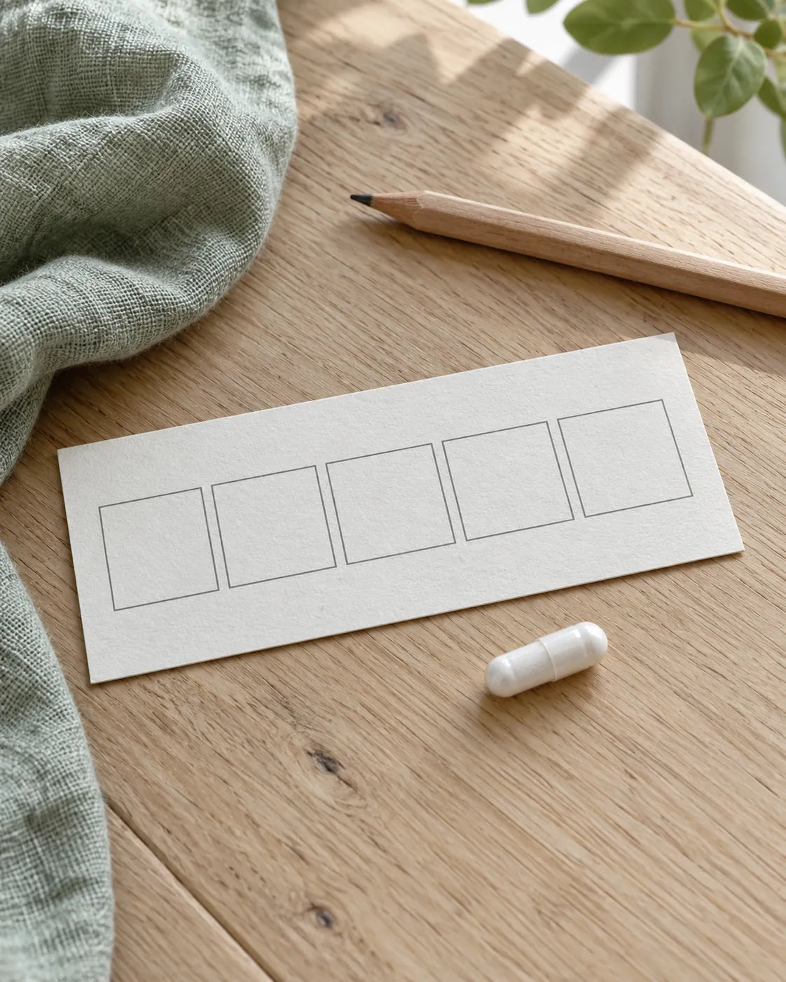 Eine Kapsel neben fünf leeren Kalenderfeldern auf einem Holztisch