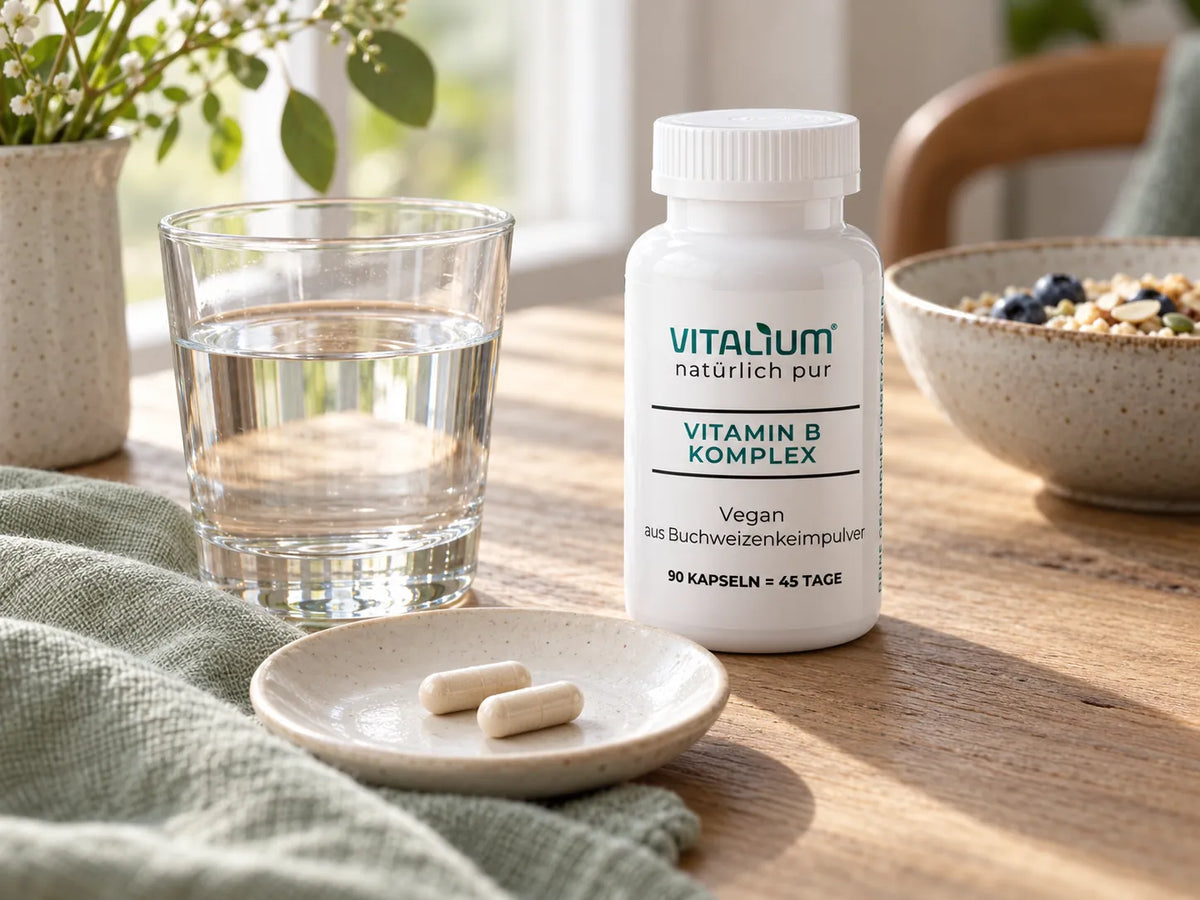 Vitamin B Komplex Dose mit zwei Kapseln und einem Glas Wasser am Frühstückstisch